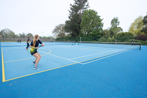 children playing tennis on a state-of-the-art tennis court at a private school